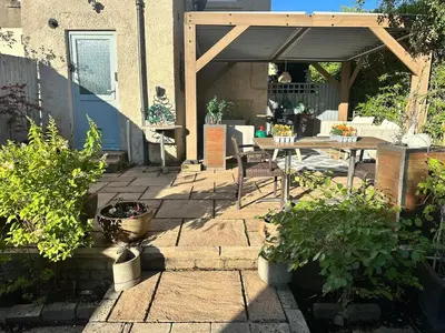 a patio with a table and a wooden pergola at Peaceful and Stylish Garden Flat Close to Transport and City Centre in Glasgow