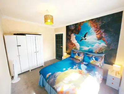 a bedroom with a blue bed with a painting on the wall at The Puffins - Largs 2-Bedroom Ground Flat in Largs