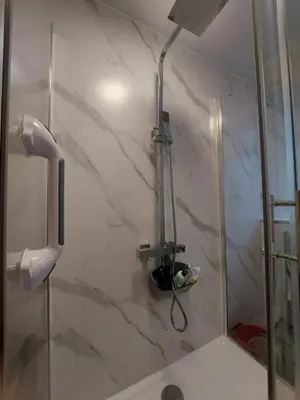 a shower in a bathroom with a marble wall at The Puffins - Largs 2-Bedroom Ground Flat in Largs