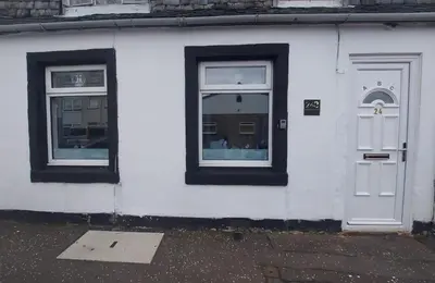 a white building with two windows and a door at The Puffins - Largs 2-Bedroom Ground Flat in Largs
