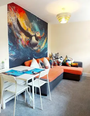 a room with a bed and a table and a painting at The Puffins - Largs 2-Bedroom Ground Flat in Largs