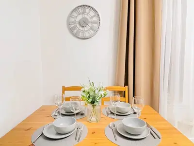 a table with plates and glasses and a clock on the wall at Lovely 1-bedroom Apt in Glasgow City near Subway in Glasgow