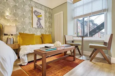 a bedroom with a bed and a table and a window at City Oasis Craigpark Residence in Glasgow