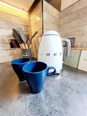 two blue cups sitting on a counter with a coffee maker at Modern Apartment - FREE parking in Glasgow
