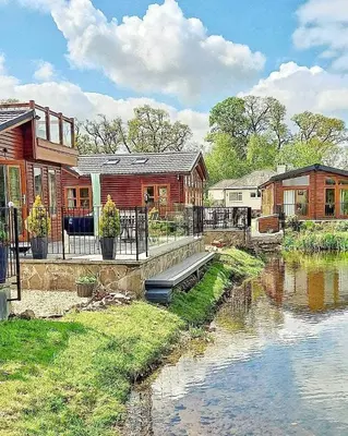 a house with a river in front of it at Lakeside Lodge - Lakeside Lodge Retreat - Golf & Spa, Gleneagles in Dunning