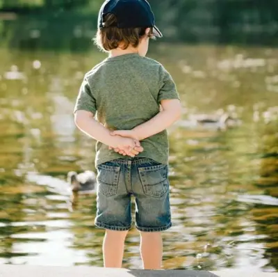 a young child standing on a rock near the water at Lakeside Lodge - Lakeside Lodge Retreat - Golf & Spa, Gleneagles in Dunning