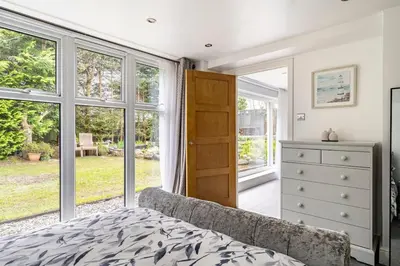 a bedroom with a bed and a dresser and windows at 2 Bedroom Garden Flat in Bearsden