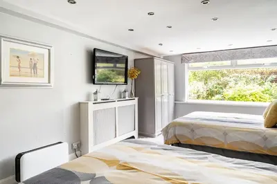 a bedroom with two beds and a tv on the wall at 2 Bedroom Garden Flat in Bearsden