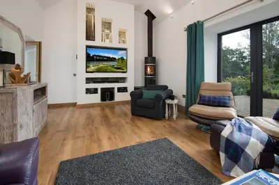 a living room with a couch chairs and a tv at Arrochar House in Tarbet