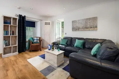 a living room with a black leather couch and a table at Arrochar House in Tarbet