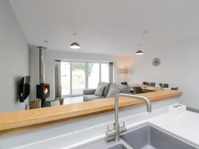 a kitchen and living room with a couch and a fireplace at Beach House in Stranraer