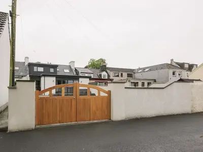 a wooden fence with a wooden gate in front of houses at Beach House in Stranraer