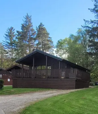a large wooden building with a black roof at Hunters Quay - Hot Tub Lodge at Limecroft 6 in Hunters Quay
