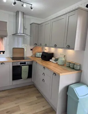 a kitchen with white cabinets and a wooden counter top at Hunters Quay - Hot Tub Lodge at Limecroft 6 in Hunters Quay