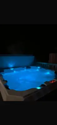a hot tub with blue water in a dark room at Hunters Quay - Hot Tub Lodge at Limecroft 6 in Hunters Quay