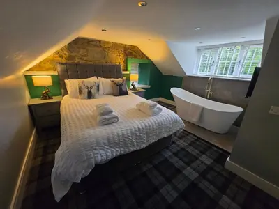 a bedroom with a large bed and a bath tub at Lochview Apartment in Tarbet