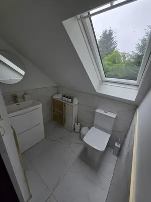 a bathroom with a toilet and a sink and a window at Lochview Apartment in Tarbet