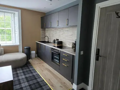 a kitchen with black cabinets and a couch in a room at Lochview Apartment in Tarbet