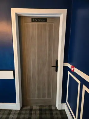 a wooden door with a sign on it in a room at Lochview Apartment in Tarbet