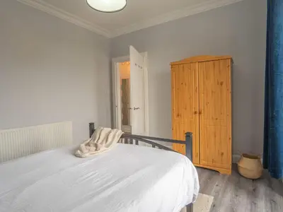 a bedroom with a bed and a wooden cabinet at Pitchside Escape in Ayr