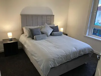a bedroom with a large white bed with blue pillows at Modern and stylish 3 bedroom 2 bathroom west end house with Free WiFi and parking in Scotstoun West Station