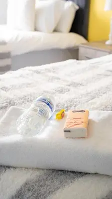 a bottle of water and a book on a bed at 3 BDR House By Caledonia Luxe Stays Short Lets & Serviced Accommodation Broxburn in Broxburn