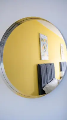 a mirror reflecting a waiting room with a chair at 3 BDR House By Caledonia Luxe Stays Short Lets & Serviced Accommodation Broxburn in Broxburn