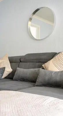 a mirror on a wall above a couch with pillows at 3 BDR House By Caledonia Luxe Stays Short Lets & Serviced Accommodation Broxburn in Broxburn