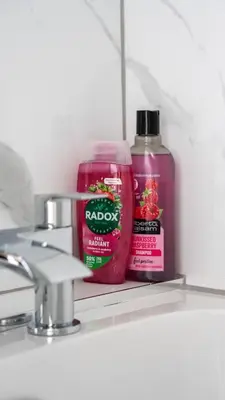a bottle of red soap and a bottle of shampoo on a sink at Pinkerton House in Dunfermline