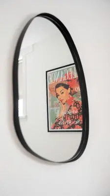 a mirror hanging on a wall with a poster of a woman at Torbrex House in Cumbernauld