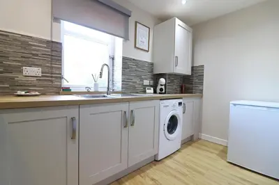 a kitchen with a sink and a washing machine at Signature - Wellhead View in Lanark