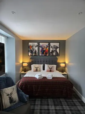 a bedroom with a bed with three pictures on the wall at Ben Lomond Apartment in Tarbet