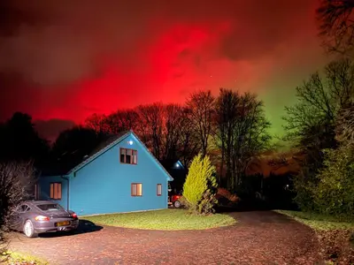 a car parked next to a blue house with a red sky at Foxglove Cottage 1 - Uk50019 in Drymen