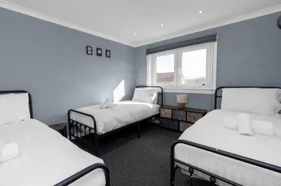 a room with three beds and a window at Free Parking - Central - Sleeps 8 - 3 Bedrooms in Livingston