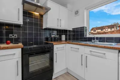 a kitchen with white cabinets and a large window at Free Parking - Central - Sleeps 6 - 2 Bedrooms in East Calder
