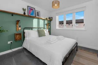 a bedroom with a bed with white sheets and a window at Free Parking - Central - Sleeps 6 - 2 Bedrooms in East Calder