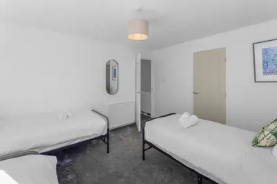 two beds in a room with white walls at Free Parking - Central - Sleeps 6 - 2 Bedrooms in Livingston