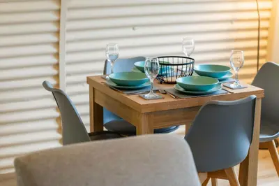 a wooden table with plates and wine glasses on it at Cultybraggan Hut 38 - Accessible in Comrie