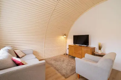 a living room with two chairs and a television at Cultybraggan Hut 38 - Accessible in Comrie