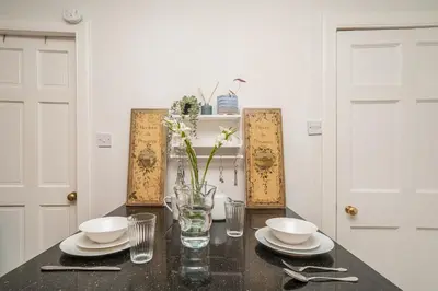 a table with plates and bowls and a vase with flowers at New Town Cottage in Edinburgh