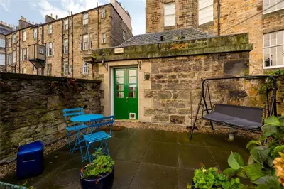a patio with blue chairs and a green door at New Town Cottage in Edinburgh