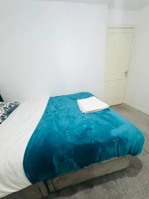 a bed with a blue blanket and a book on it at Private Room in Glasgow City in Hillfoot
