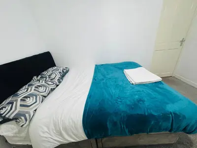 a bed with a blue blanket on top of it at Private Room in Glasgow City in Hillfoot