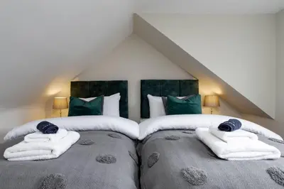 two beds in a room with green and white towels at Modern Comfort in Historic Callander in Stirling