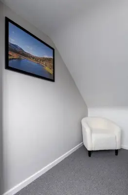 a living room with a tv and a white chair at Modern Comfort in Historic Callander in Stirling