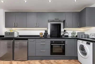 a kitchen with gray cabinets and a washer and dryer at Modern Comfort in Historic Callander in Stirling