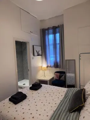 a bedroom with a bed with two black towels on it at Balloch But & Ben in Balloch