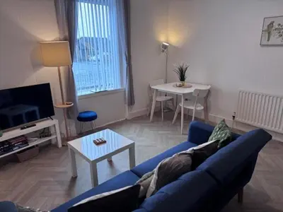 a living room with a blue couch and a table at Balloch But & Ben in Balloch
