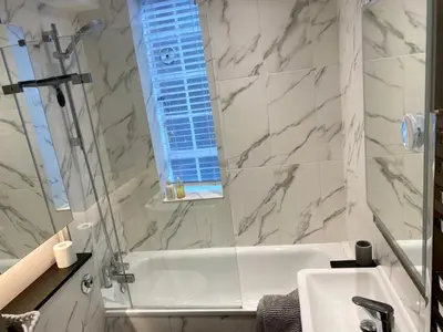 a bathroom with a tub and a sink and a window at Elegant Chelsea Apartment in Moffat