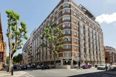 a large building on a city street with cars parked at Elegant Chelsea Apartment in Moffat